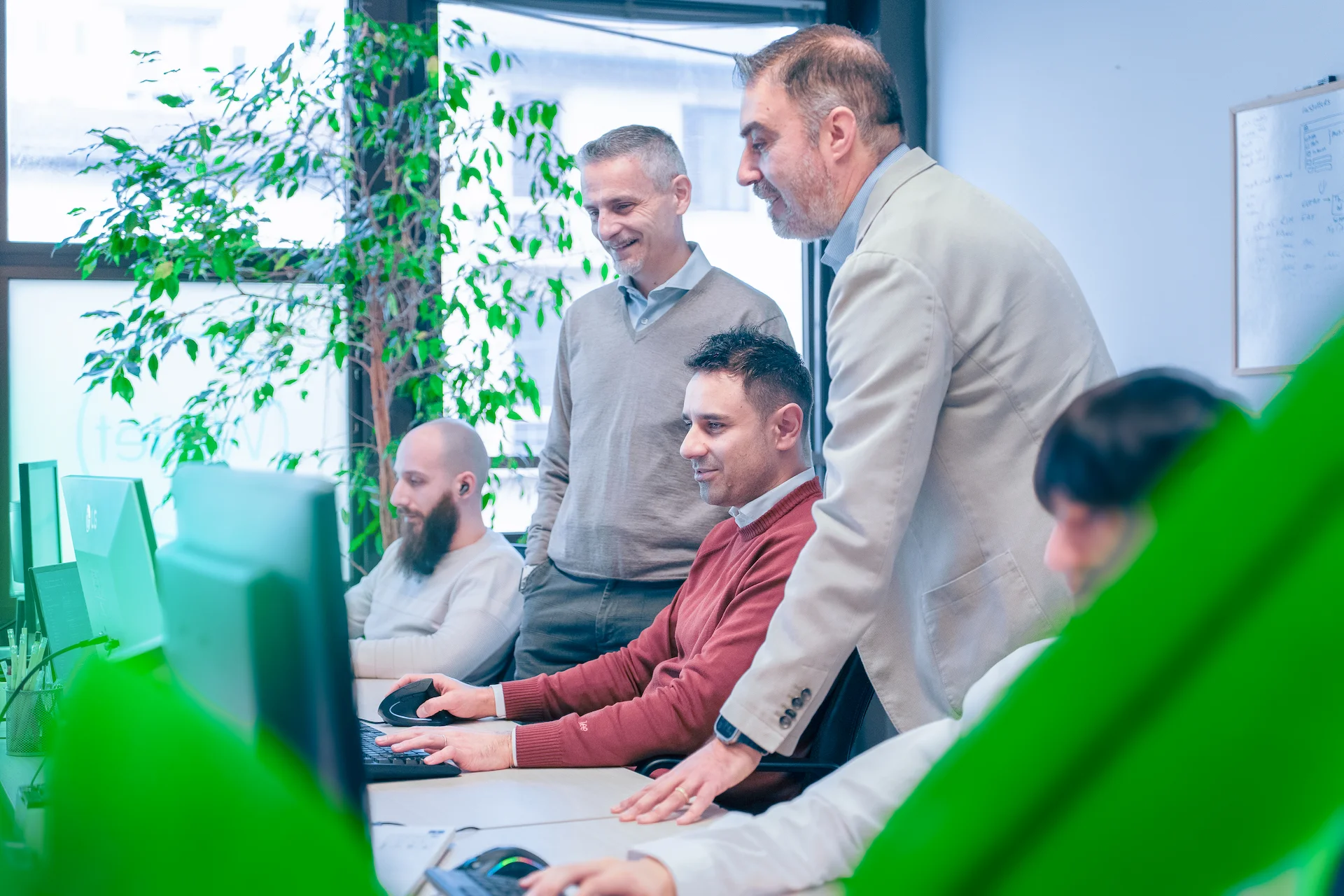 Team di Winet al lavoro su progetti software in un ufficio luminoso, con più colleghi che discutono e collaborano davanti ai monitor, riflettendo la cultura collaborativa e le opportunità di carriera dell’azienda.
