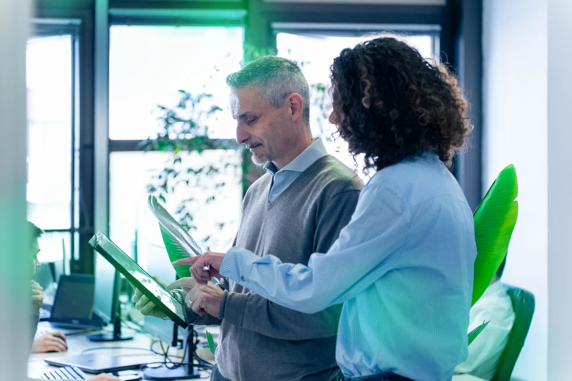 Due professionisti di Winet che consultano un tablet in ufficio, discutendo strategie e soluzioni innovative per il progetto BPM destinato a Banco BPM.