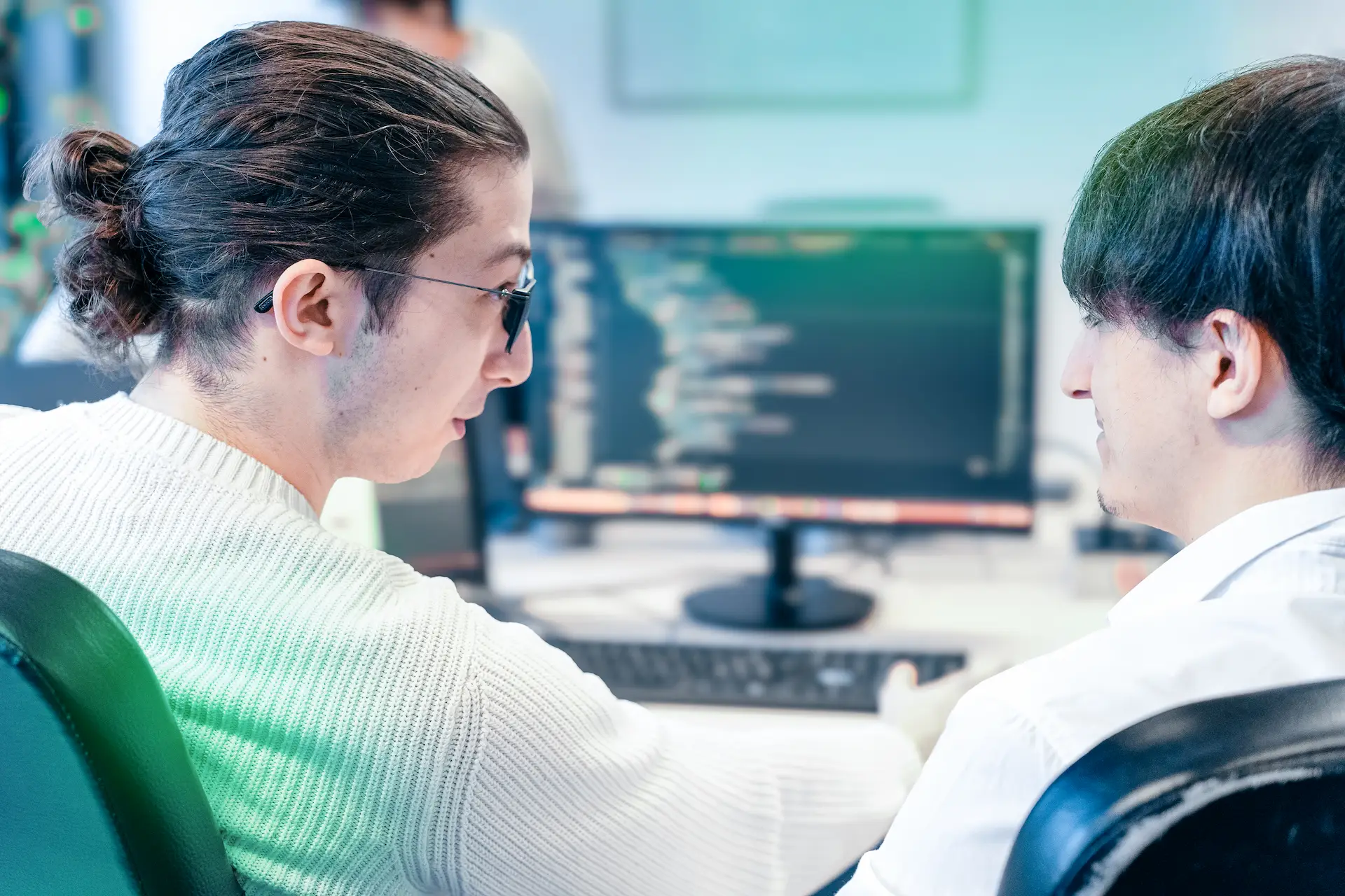 Due sviluppatori discutono di soluzioni di consulting software davanti a un monitor, dimostrando un software consulting service in linea con la search intent, fornito dalle software consulting companies.